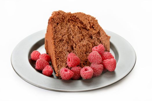 A piece of chocolate cake and fresh raspberries on a place isolated on white.