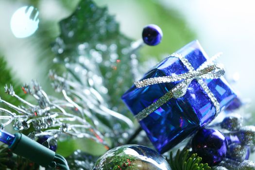 Blue present ornament nestled in CHristmas tree.