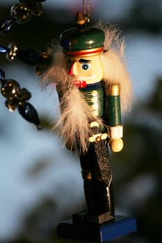 Nutcracker ornament hanging in shadows of Christmas tree at night.