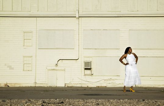 African American woman waiting beside an abandoned warehouse.