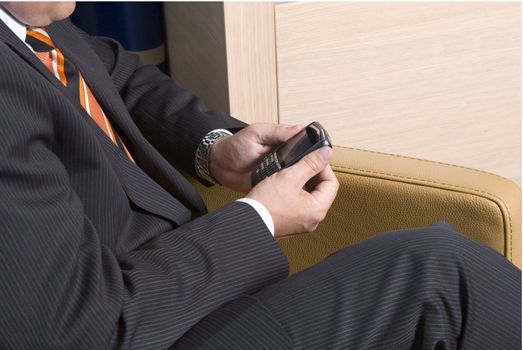 Businessman sitting in a chair texting on his mobile phone