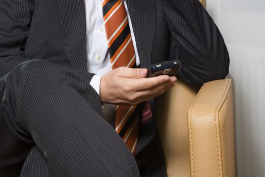 Businessman sitting in chair waiting for email on his mobile