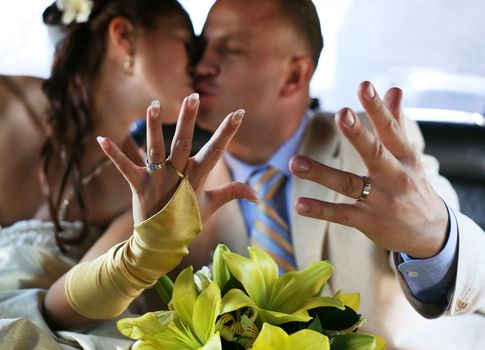 The groom and the bride kiss, showing wedding rings