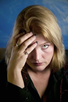 Close up of blonde woman in a studio setting touching her temple.