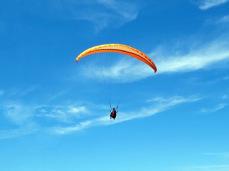 Paraglider on a blue sky with thin clouds