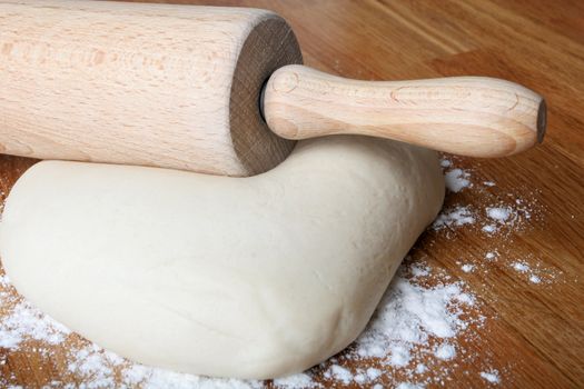 bread dough on wooden kitchen counter with rolling pin