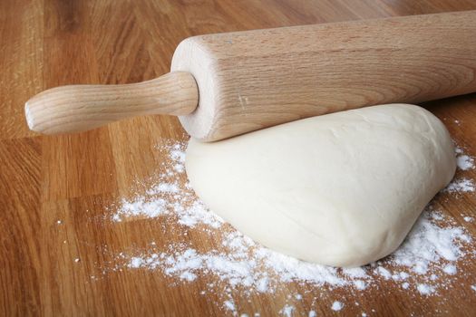 bread dough on wooden kitchen counter with rolling pin