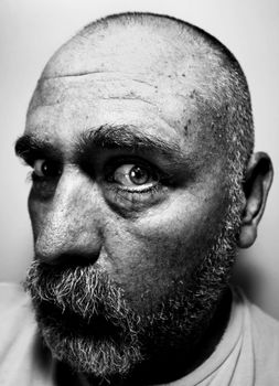 Black and white portrait of a suspicious bald man with a beard.