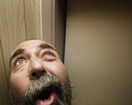 Man with a beard looks up towards a light source.