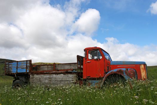 Broken down vintage truck standing in a field of grass in summer