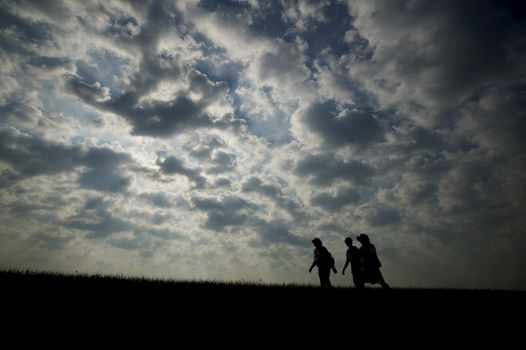 Three walkers silhoutted against the sky at dusk.