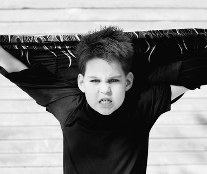 Young boy with his shirt stretched behind his head and a scary look on his face.