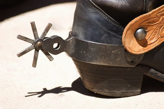 Back of a cowboy boot with a spur in bright sunlight.