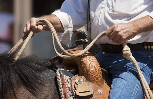 Close up on hands of a cowboy on horseback.