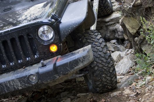 Headlight and grille on a four-wheel drive vehicle traveling over rocks.