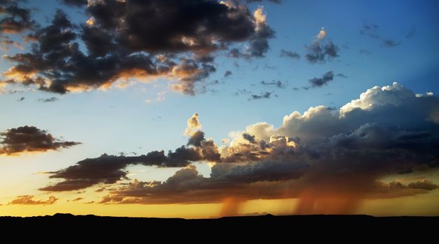 Rain clouds and a storm in the distance at sunset.