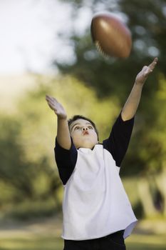Young boy with arms stretched out to catch a football