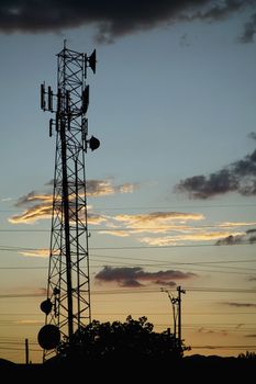 Communications tower and powerlines silhouetted against a late evening sky.