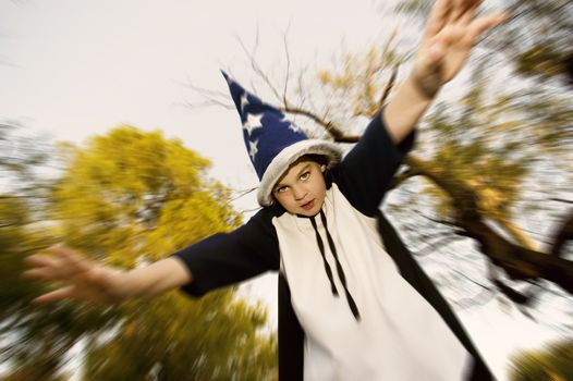 Young boy in a wizard costume with his arms outstretched