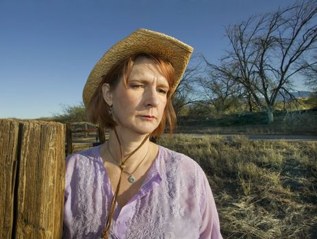 Portrait of a woman in a purple shirt and cowboy hat on a ranch.