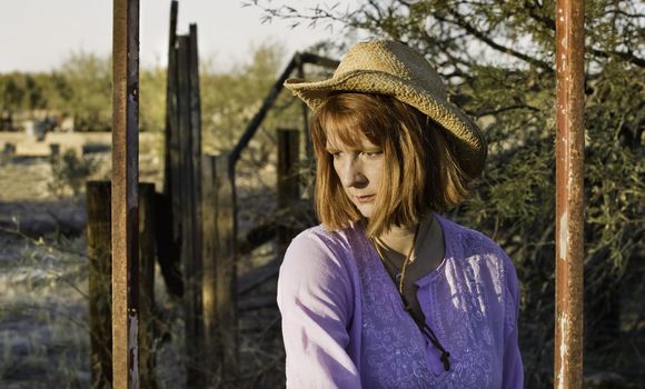 Woman wearing a cowboy hat in a rural setting.