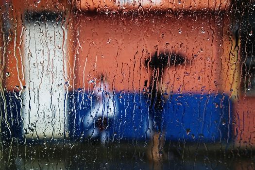 Rain on a window looking out to people in a street scene.