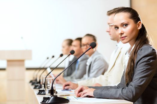 group of business people sitting at the tables at the presentation, woman looking at the camera