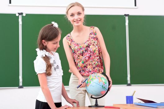 teacher explains the lesson in geography, stand near the school globe