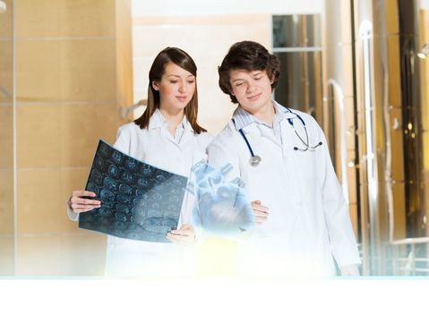 two doctors stand near glowing table discussing. projected objects on a desk