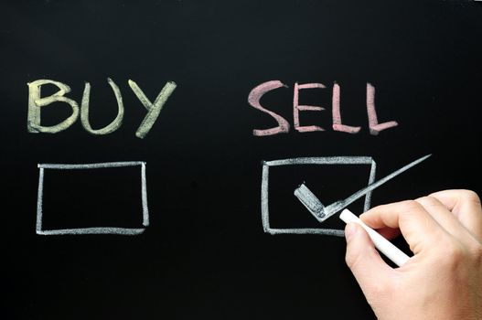 Buy or sell check boxes on a blackboard. Finance, economy, stock or real estate concept - time to buy or sell.