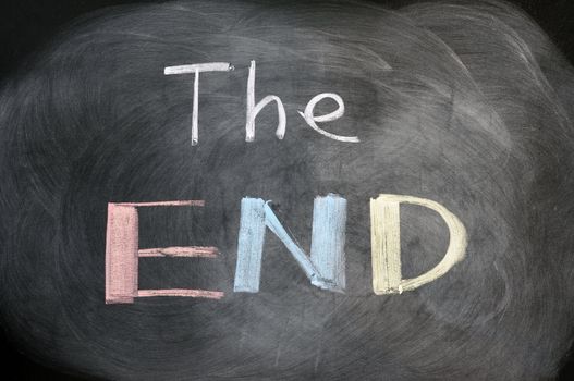 The end - handwritten with colorful chalk on a blackboard with eraser smudges 