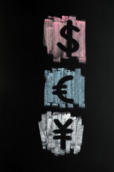Symbols of Dollar, Euro and Yuan drawn with colorful chalk on blackboard