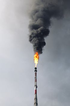 refinery flame and black smoke in the sky