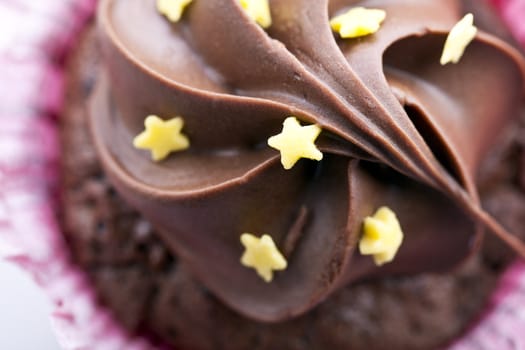 Close-up of chocolate cupcake frosting with yellow stars.   Angle from directly above.