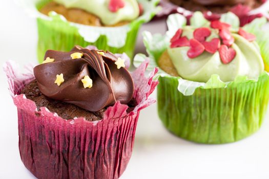 Chocolate and vanilla cupcakes in red and green cupcake wrappers topped with candies.