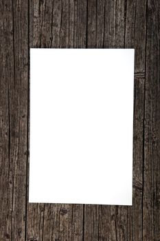 Blank clean white sheet of paper on a weathered stained textured wood background with copy space for your text
