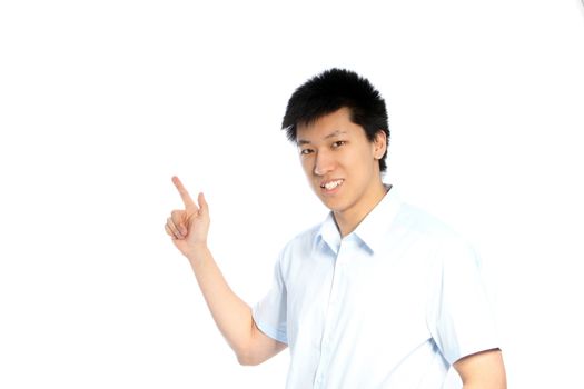Smiling young Asian man facing the camera and pointing to the left of the frame with his finger to blank white copyspace