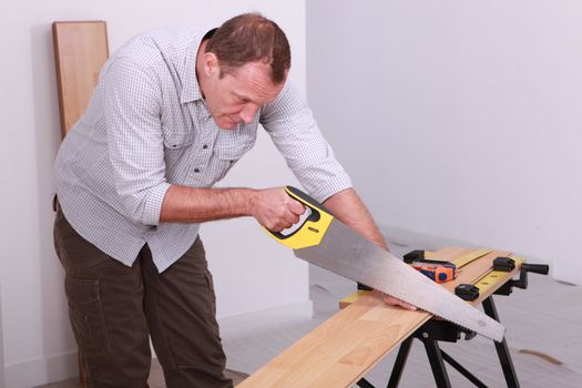 Man sawing a wooden floor