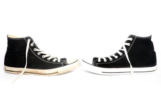 Pair of laced sneakers on a white background for casual wear arranged with their toes facing each other
