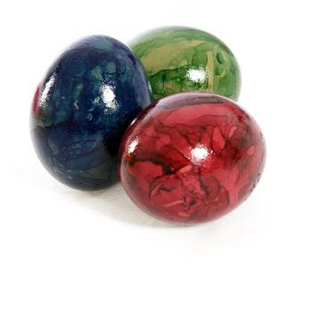 Colourful hand painted traditional Easter Eggs with a marble pattern in green , red and blue on a white studio background
