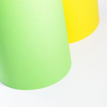 Rolls of yellow and green cardboard standing upright isolated on a white background with copyspace