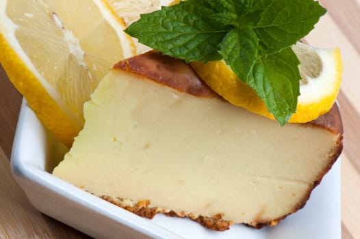 A piece of lemon cake decorated with lemon slices and mint leaves