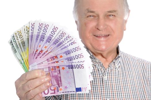Smiling senior man with a fistful of fanned 500 euro banknotes depicting wealth and security in old age through sound and prudent investments isolated on white