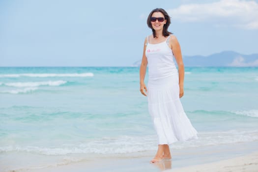 Handsome young woman walking near blue sea.
