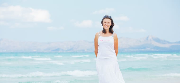 Handsome young woman walking near blue sea.