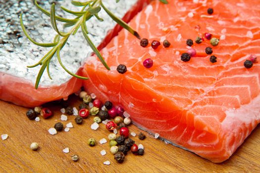 Fresh salmon fillet on wooden board with pepper and rosemary