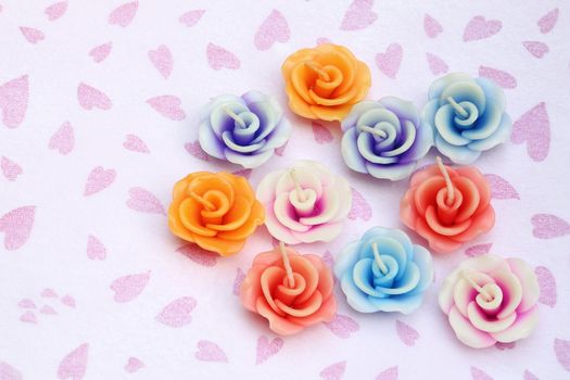 Candles in shape of flower on pink hearts and white background