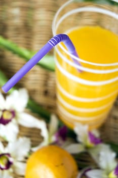 close up violet drinking straw in glass of orange juice