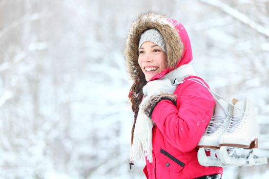 ice skating winter woman holding ice skates outdoors in snow. Beautiful young mixed race chinese asian / caucasian woman