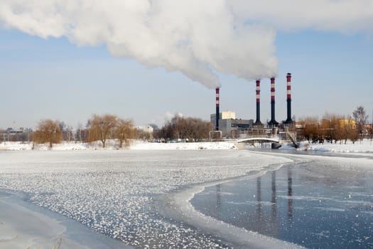 industrial cityscape with frozen river and power plant chimneys on backward in Minsk, Belarus